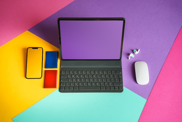 Um computador portátil, smartphone e unidades SSD em um fundo colorido, apresentando uma tela em branco para fins de mockup.